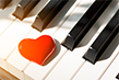 A red heart sitting on top of a piano keyboard.