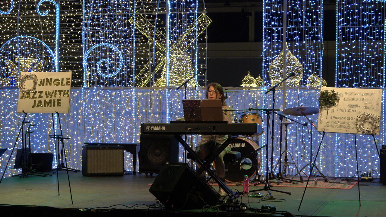 A woman sitting at a keyboard in front of a stage.