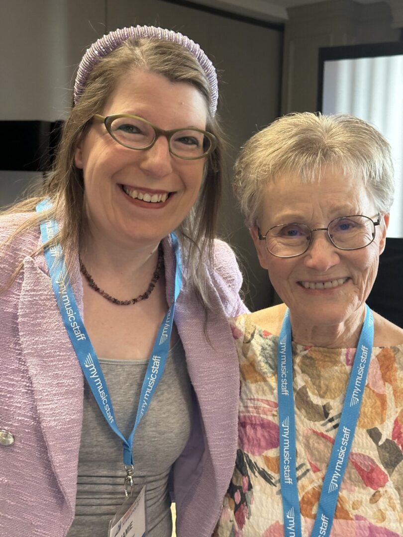 two women with specs are smiling and posing for a photo