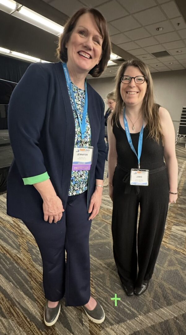 Two women smiling at a conference.