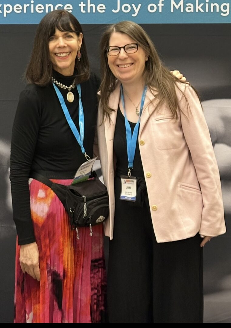 Two women smiling at a conference event.