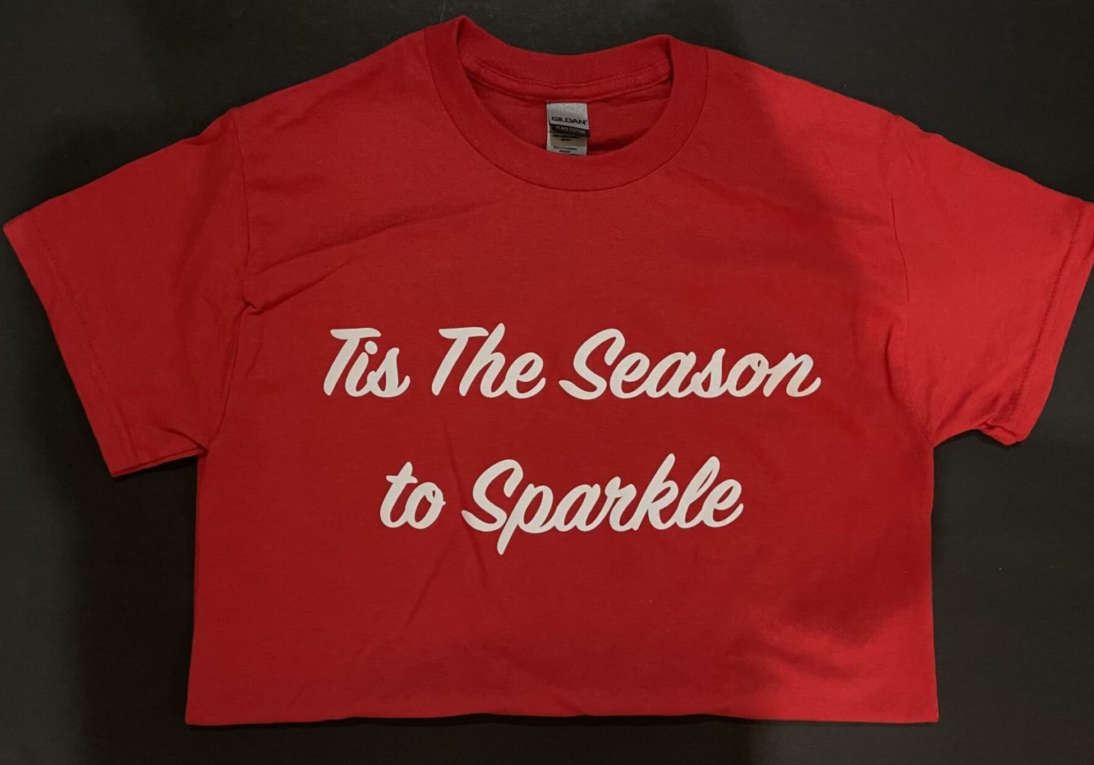A red shirt that says tis the season to sparkle.